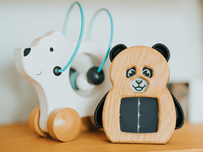 Capteur de qualité d'air en bois, en forme de panda avec un panneau solaire et un visage souriant, posé sur une étagère en bois avec un jouet pour enfant en forme d'ours polaire